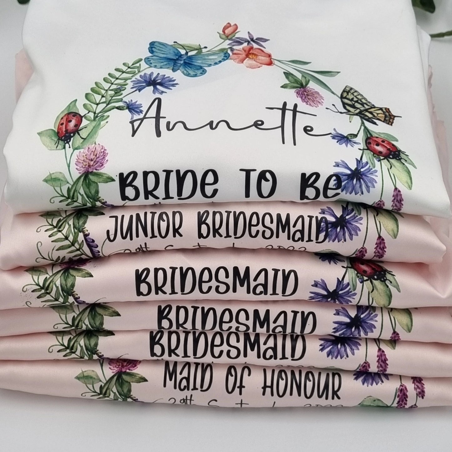 Blush pink and white bridesmaids and brides robes with butterfly wreath design and personalised with name and title