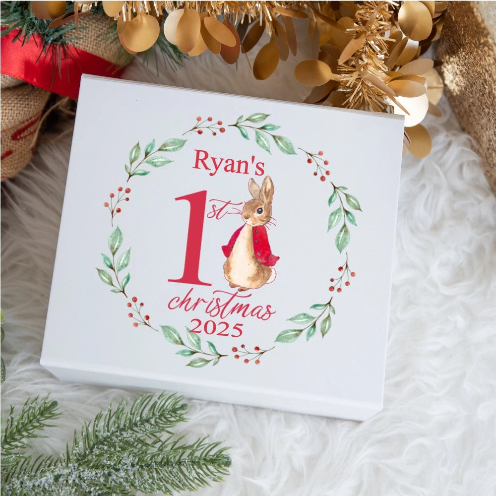 Personalised baby keepsake box featuring a watercolour bunny wearing a red jacket inside a wreath of green leaves and red berries, with the text ‘Ryan’s 1st Christmas 2025’