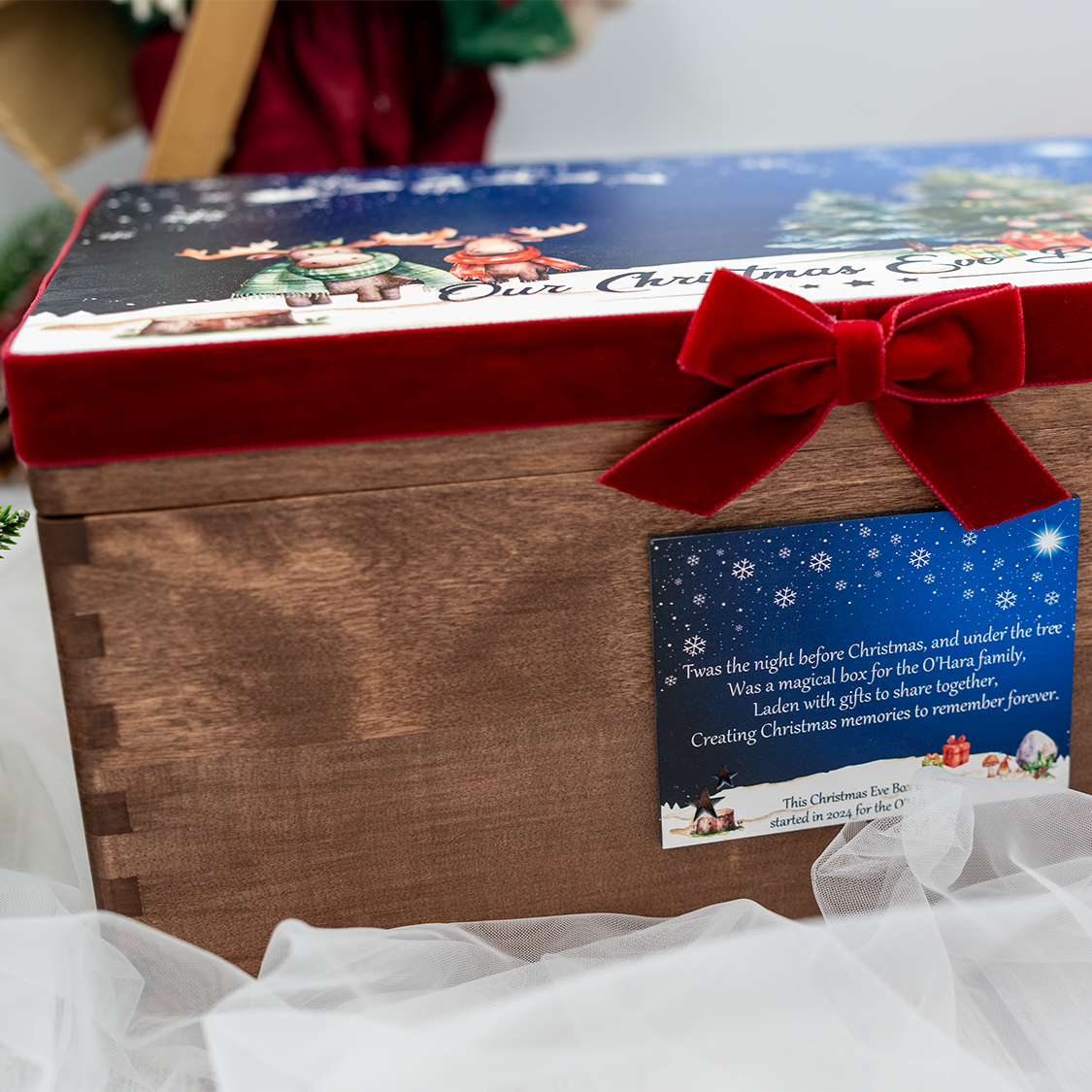 Custom Christmas Eve Box by Hana Lee Studios – wooden box with festive scene and ribbon, styled with snowman and holiday greenery.