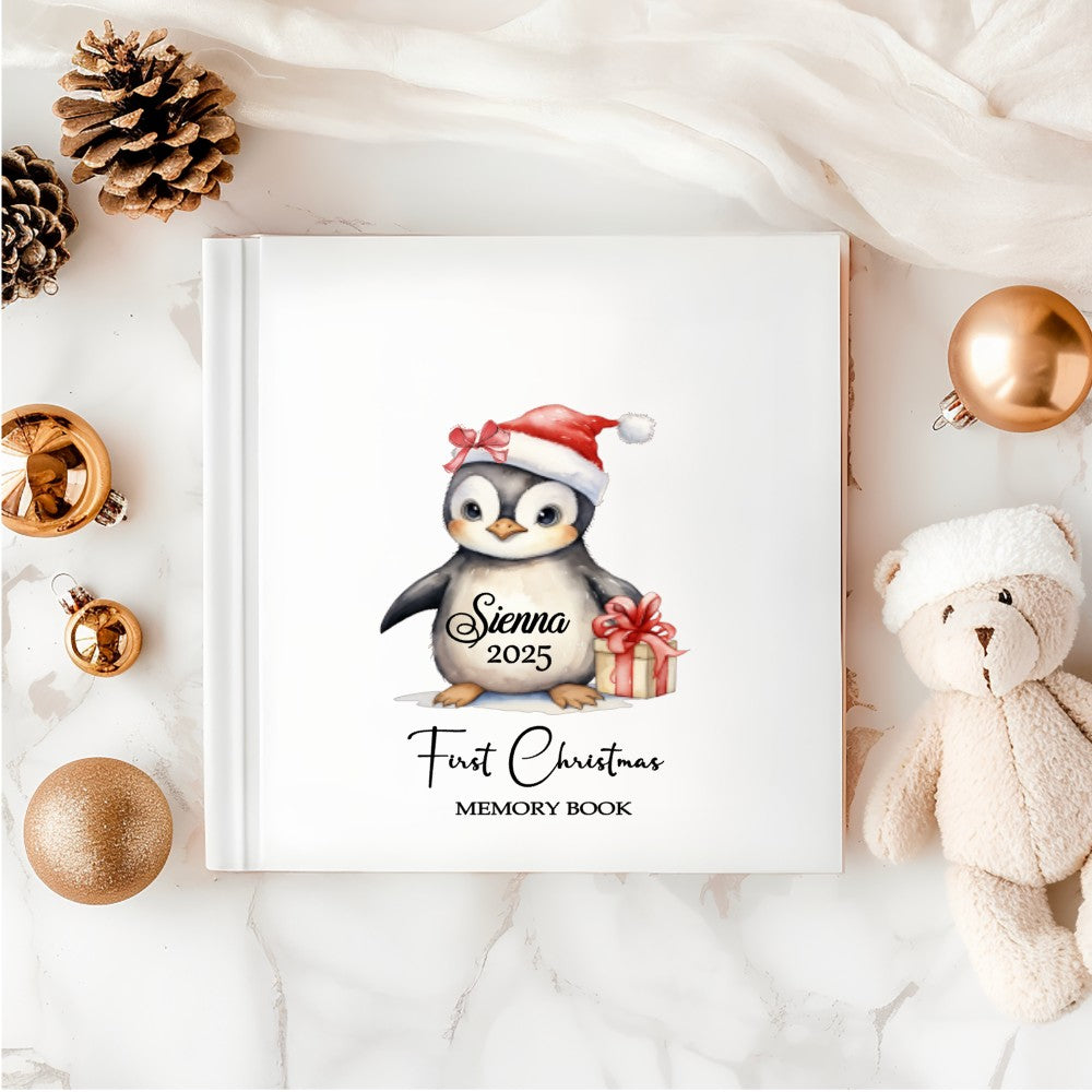 Personalised Baby’s First Christmas Memory Book with penguin in Santa hat – white hardback keepsake.