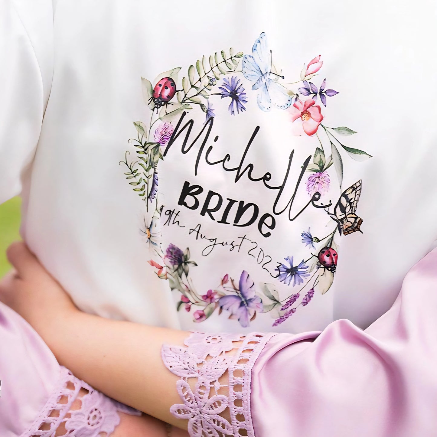 Personalised white bridal robe with floral wreath design, featuring name, title and wedding date printed on the back, created by HanaLee Studios in Co. Meath, Ireland.