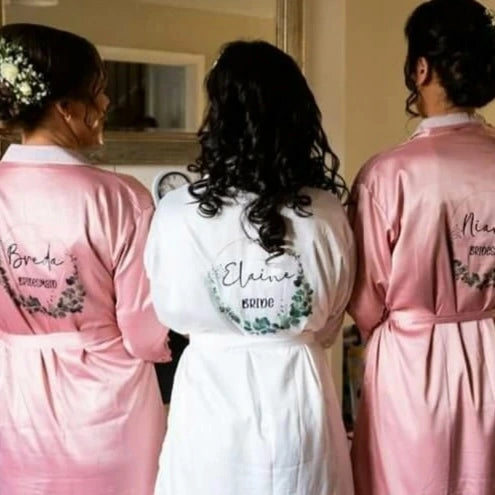 Bride and bridesmaids wearing personalised satin lace wedding robes in dusty rose pink and white