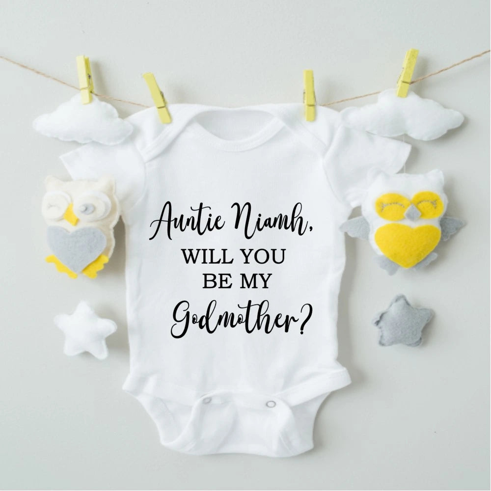 White baby onesie with 'Auntie Niamh, will you be my Godmother?' text.