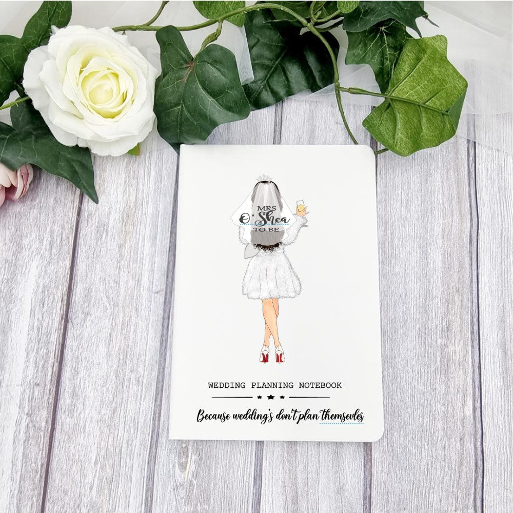 White A5 notebook with bride design and personalised with name on the brides veil. Caption at the bottom of the book which reads wedding planning notebook - because weddings don't plan themselves