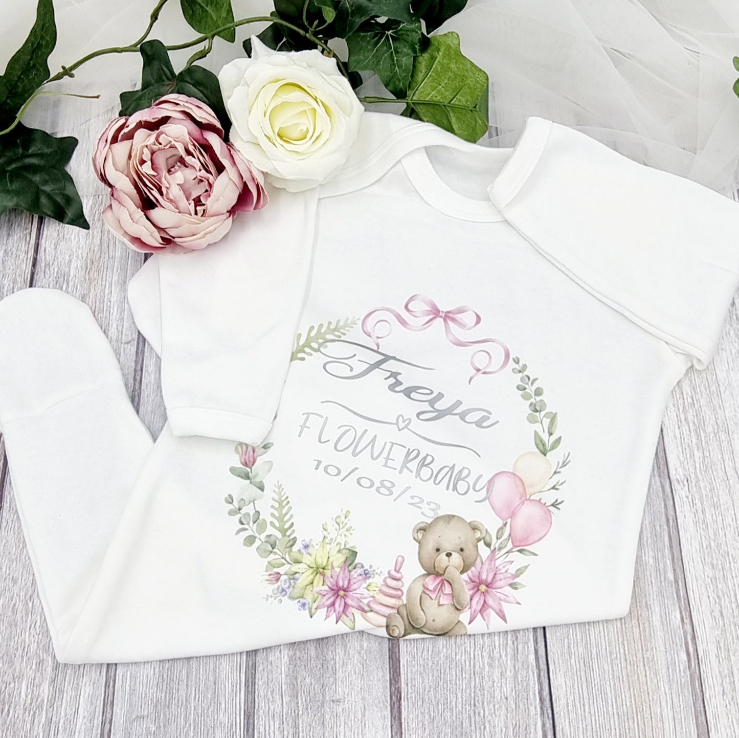 Personalised white Flowerbaby babygrow with teddy and floral wreath design, customised with name and date, printed and finished in Ireland by HanaLee Studios.