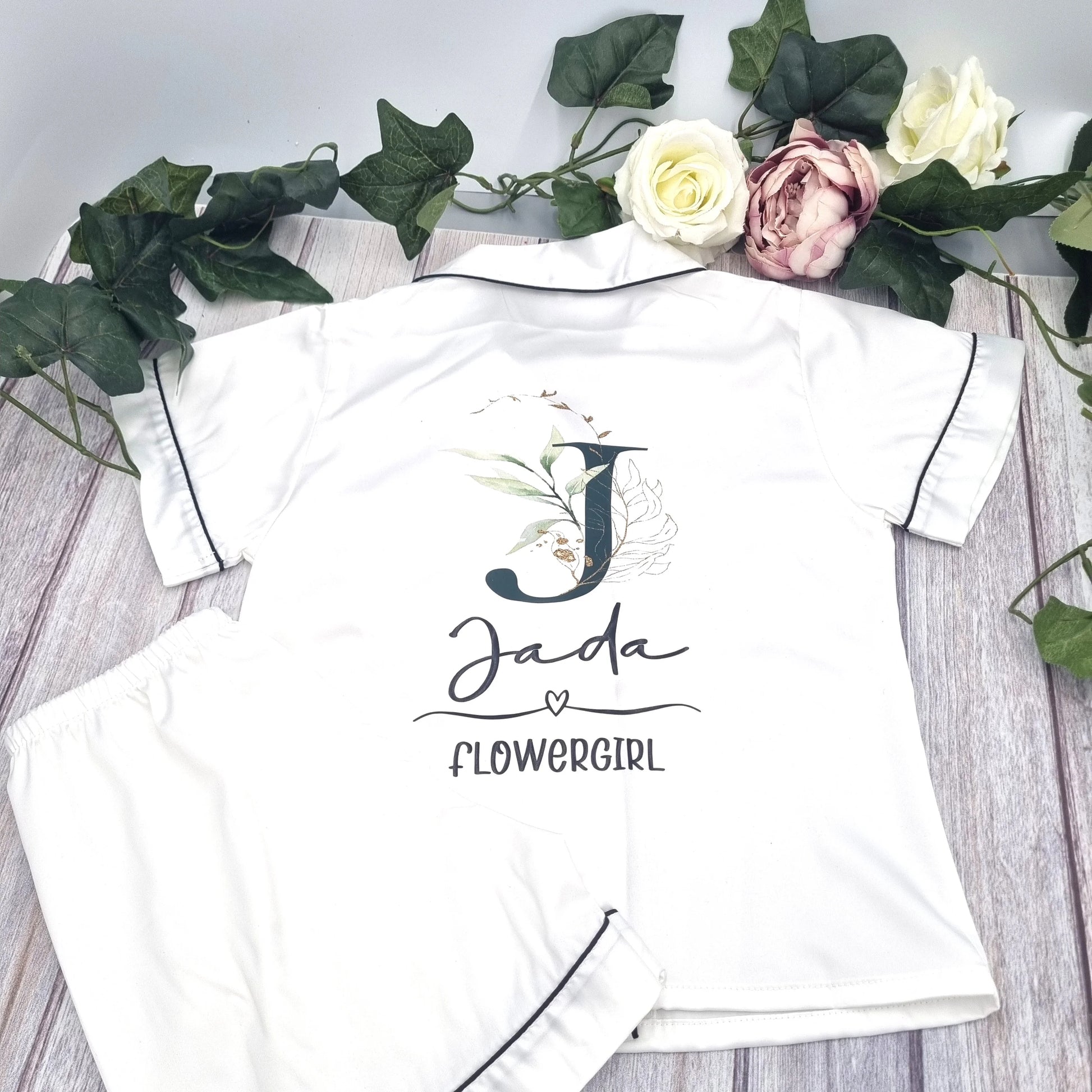 White satin flowergirl pyjamas with eucalyptus floral initial design and personalised name print, designed, printed and finished in Ireland by HanaLee Studios.