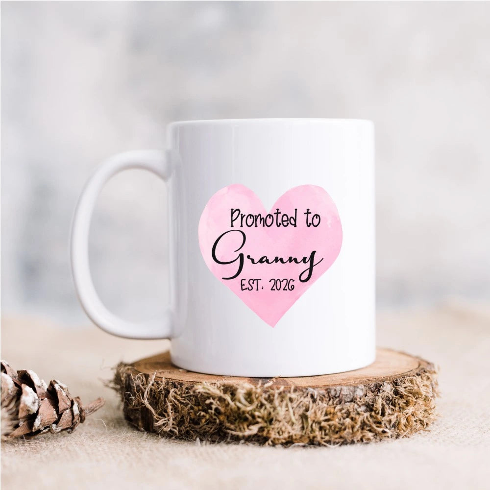White ceramic mug with pink heart and the words Promoted to Granny Est. 2026, personalised new grandparent gift handmade in Ireland.