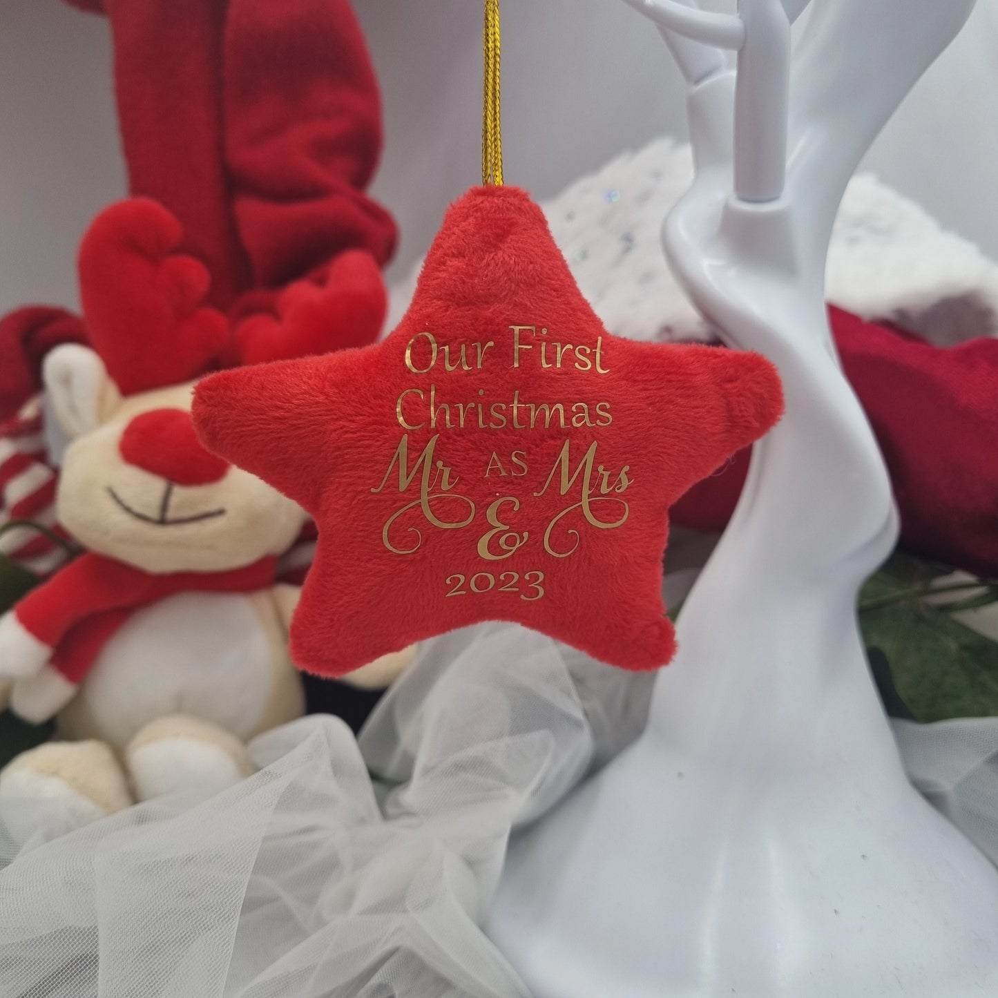 Red star ornament with 'Our First Christmas Mr & Mrs & 2023' text, surrounded by festive decorations.