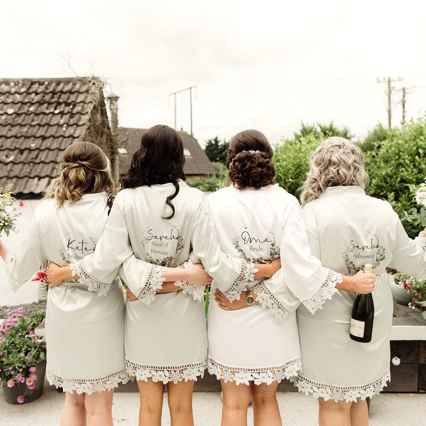 Bride and bridesmaids wearing white and sage green satin robes on wedding morning personalised by HanaLee Studios