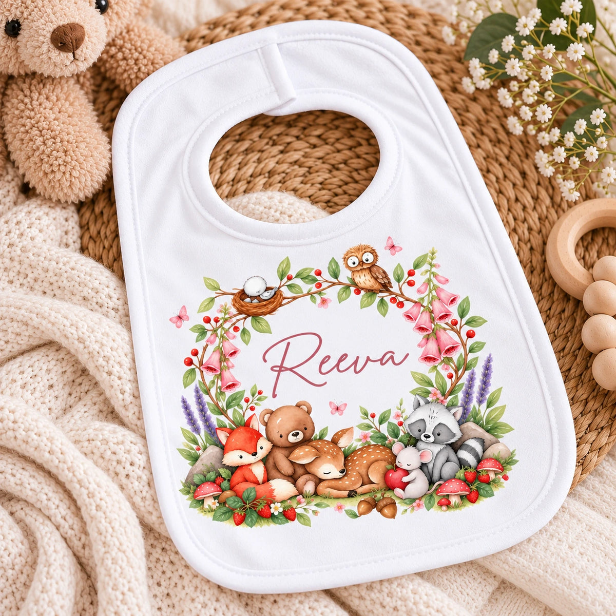 White personalised baby bib with name, pink woodland flowers and illustrations of a fox, deer, bear, owl, raccoon and mouse.