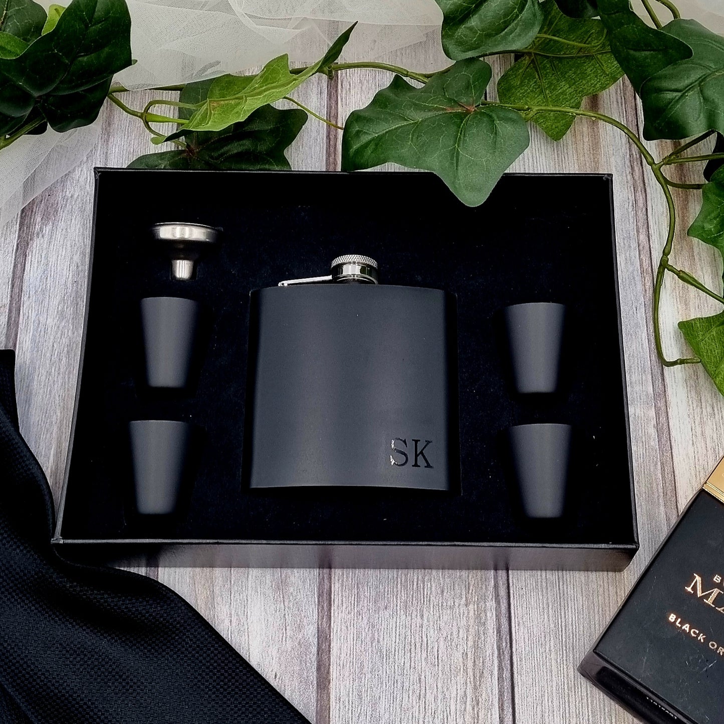 HanaLee's black hip flask gift set with initials on the bottom right hand corner of the hip flask. Set comes with 4 black stainless steel shot glasses and a funnel and it boxes in a rigid black gift box