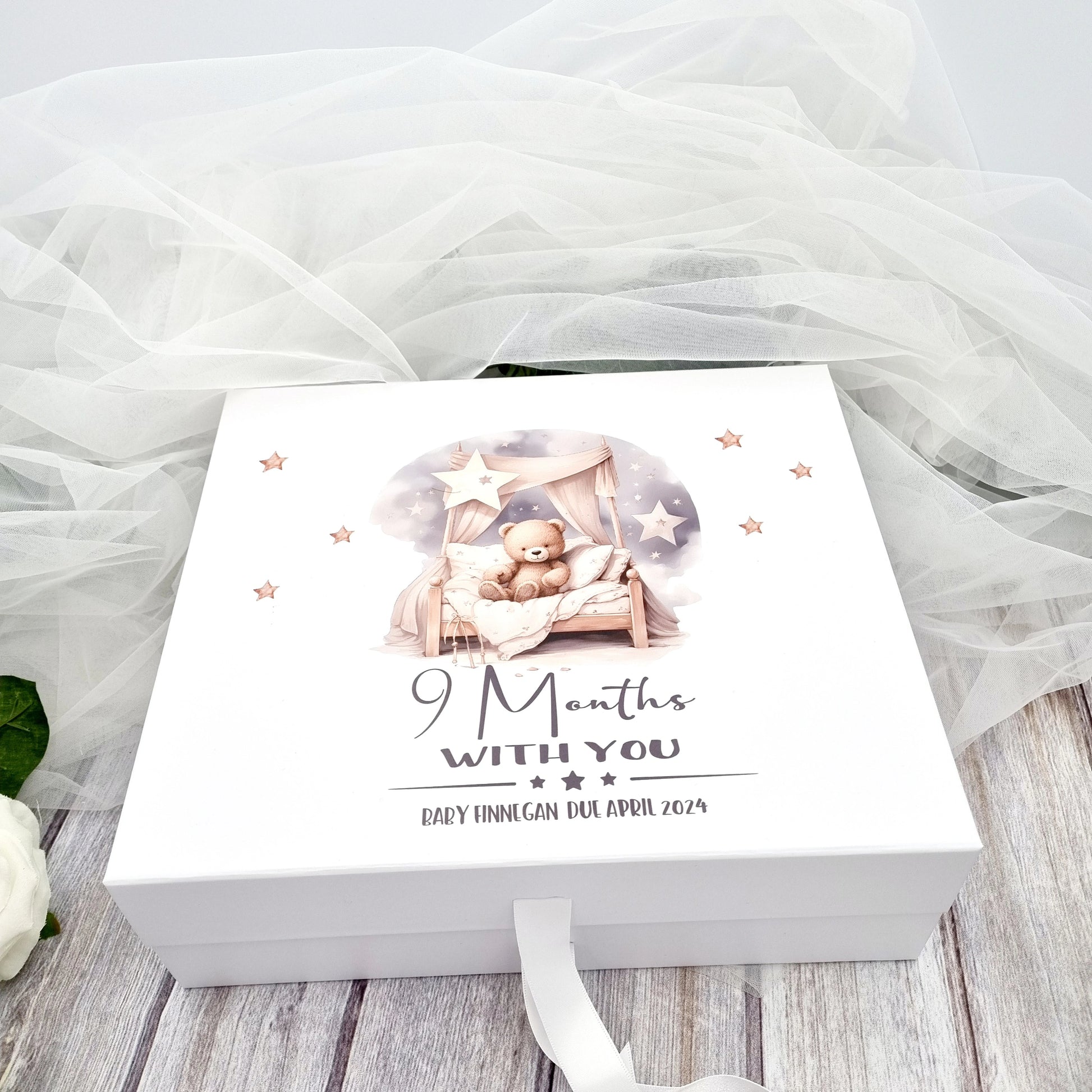 White gift box with design of teddy sitting on a bed with caption 9 months with you and the baby's details for baby shower. 