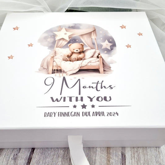 White gift box with design of teddy sitting on a bed with caption 9 months with you and the baby's details. 