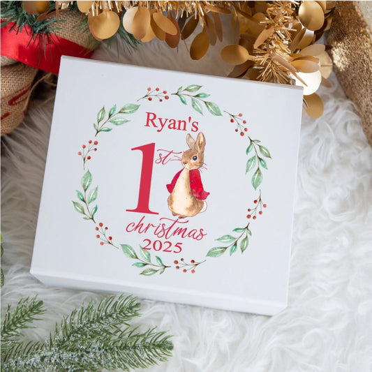 Personalised baby keepsake box featuring a watercolour bunny wearing a red jacket inside a wreath of green leaves and red berries, with the text ‘Ryan’s 1st Christmas 2025’