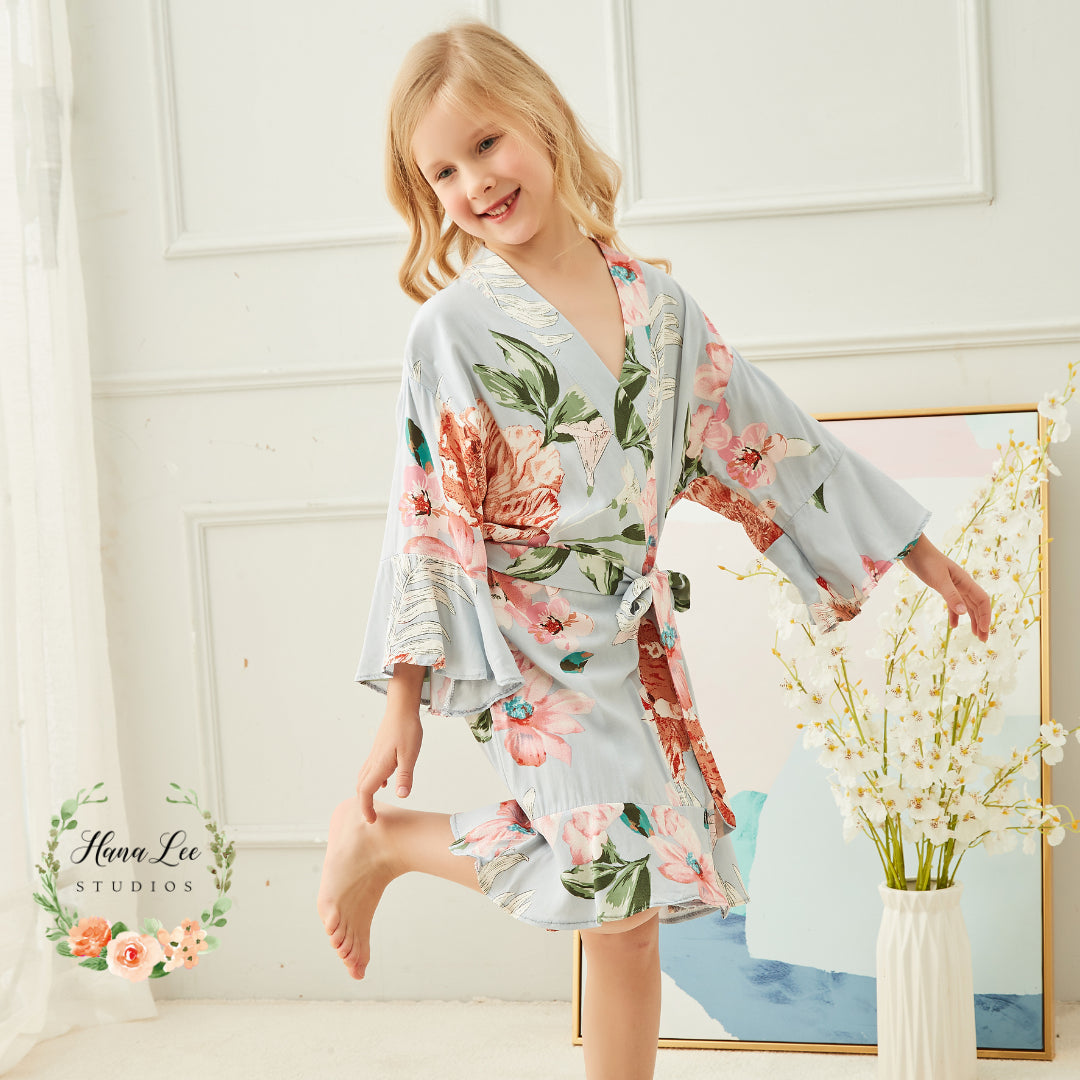 Child wearing personalised dusty blue floral satin wedding robe — matching flowergirl robe from HanaLee Studios, Co. Meath