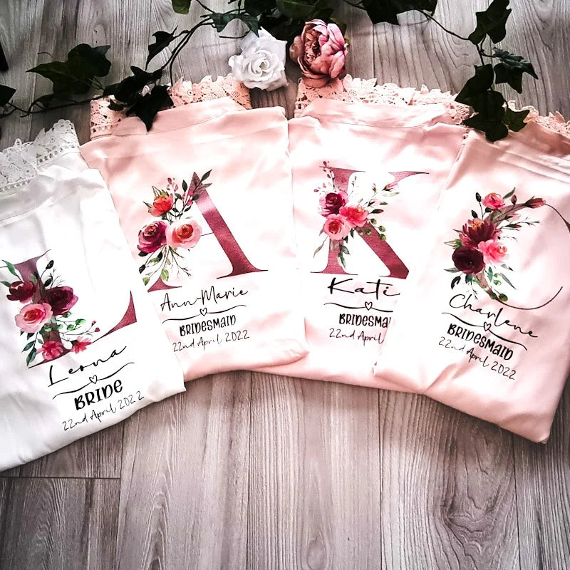 Set of personalised wedding robes for bride and bridesmaids featuring floral initials and lace trim – designed and finished in Ireland by HanaLee Studios.
