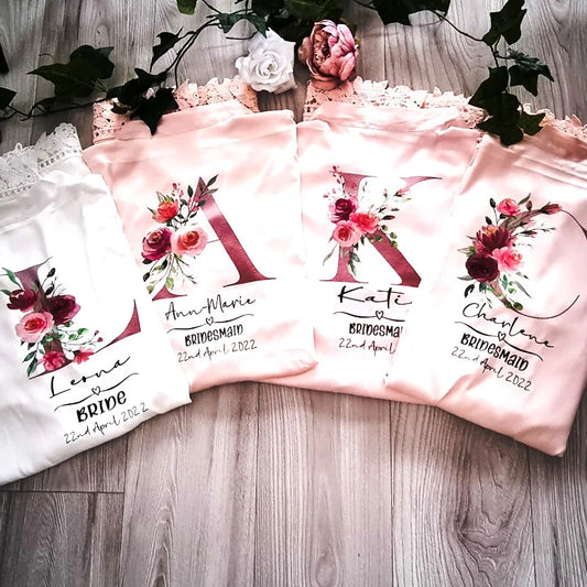 Set of personalised wedding robes for bride and bridesmaids featuring floral initials and lace trim – designed and finished in Ireland by HanaLee Studios.
