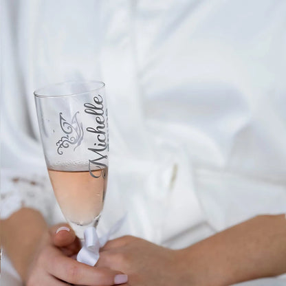 Bride in her white robe holding a champagne flute personalised with her name. 