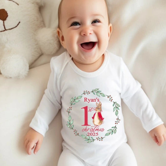 A baby in a white babygro printed with a cute rabbit wreath design personalised with baby's name and first christmas 2025 