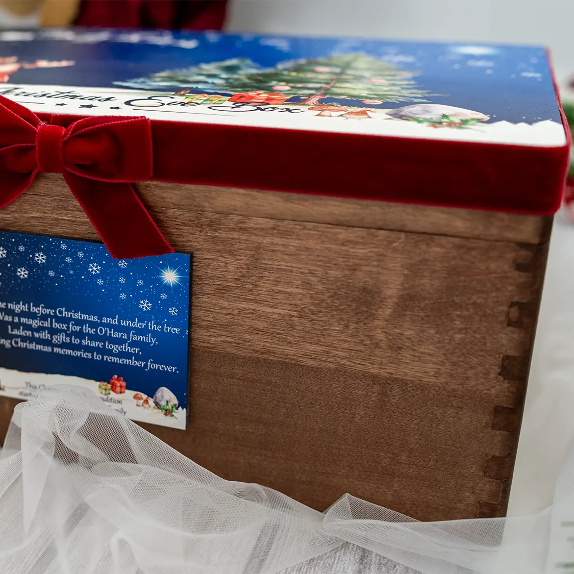 Side view of personalised Christmas Eve box from HanaLee Studios featuring rustic wooden storage box, Christmas illustrations and festive red velvet ribbon.