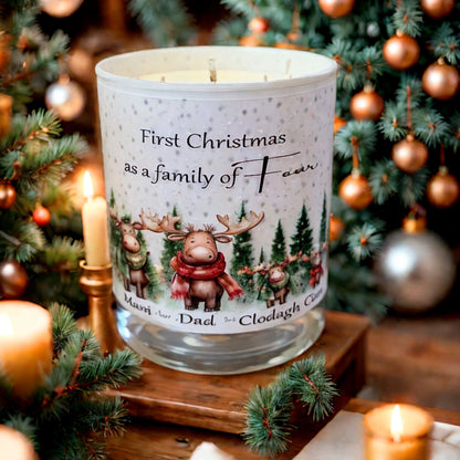 Personalised Christmas candle with reindeer family design and the text “First Christmas as a family of four,” surrounded by festive trees and candles.