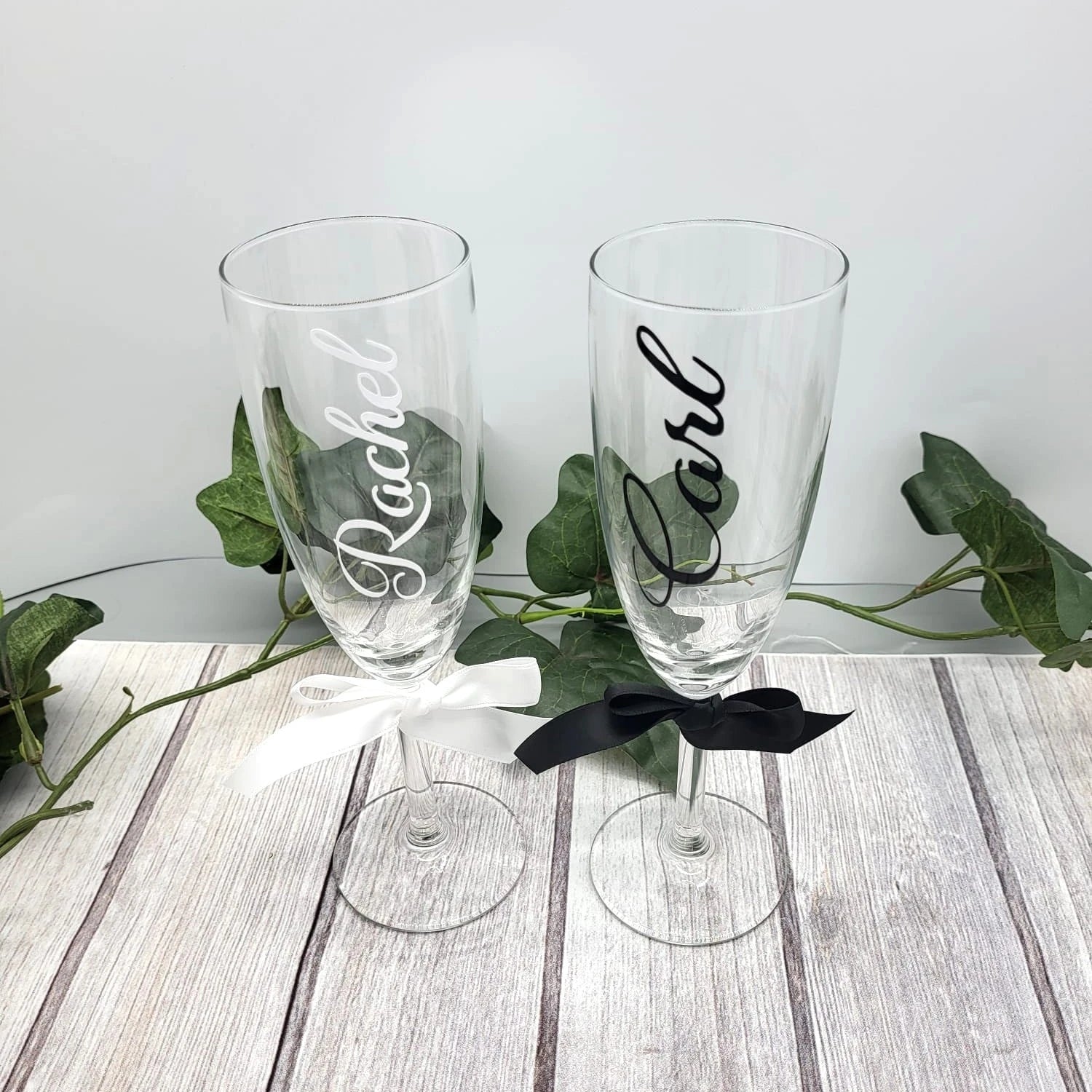 Pair of custom wedding champagne glasses with bride and groom names in black and white vinyl.