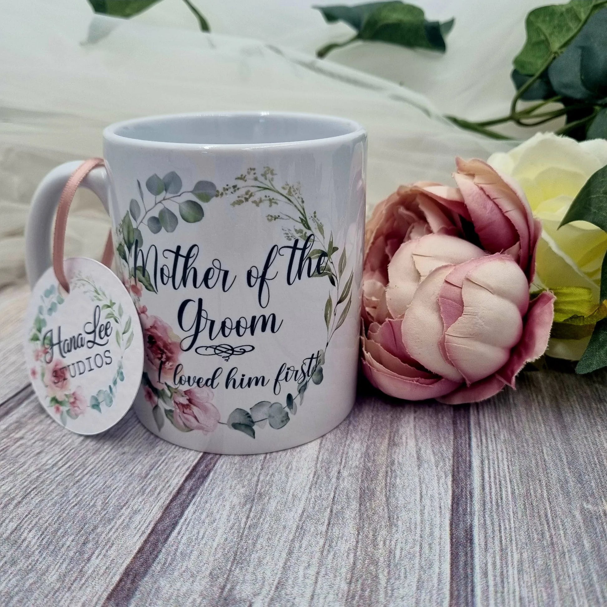 White floral Mother of the Groom mug with greenery wreath design and “I loved him first” quote, personalised wedding thank you gift from bride and groom, Irish wedding keepsake.