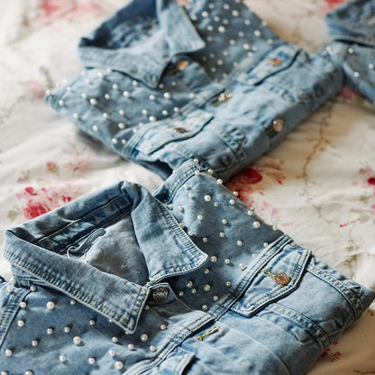 Folded personalised bridal denim jackets, laid out on the bed for the bride and her bridesmaids to wear. 