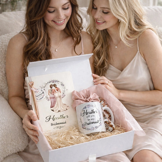 Bride giving personalised bridesmaid proposal gift box with mug and keepsake items to bridesmaid on sofa, luxury wedding bridesmaid gift by HanaLee Studios