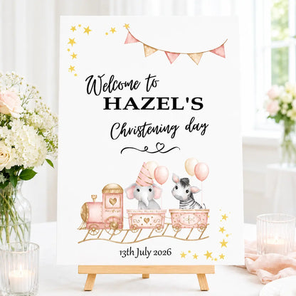 Personalised A3 christening welcome sign for a with animal train, elephant and zebra design, displayed on a small wooden tabletop easel.