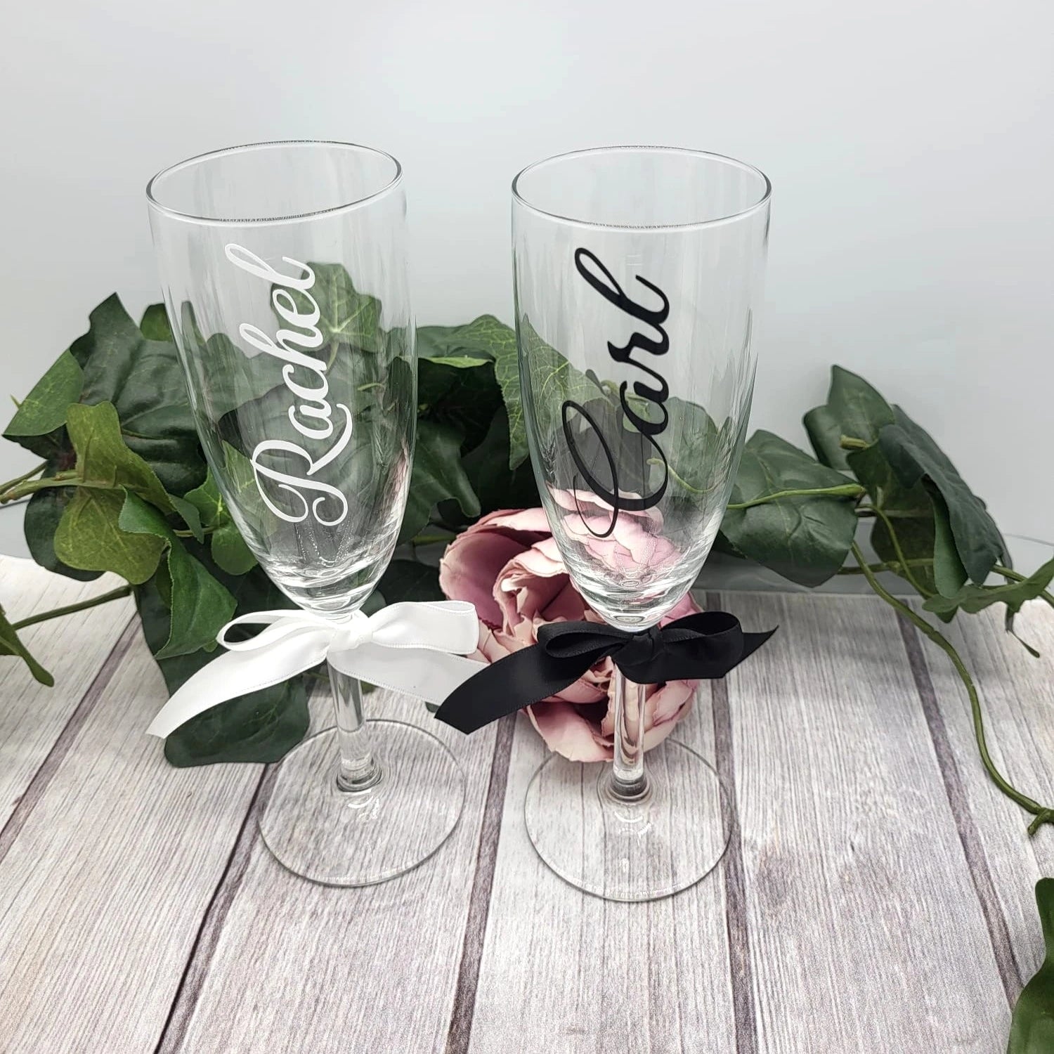 Close-up of personalised wedding flutes showing name details and satin ribbon bows.