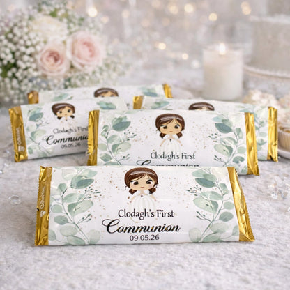 Personalised First Communion chocolate bar wrappers featuring a boys or girls communion design with custom name and date, displayed on a communion party table.