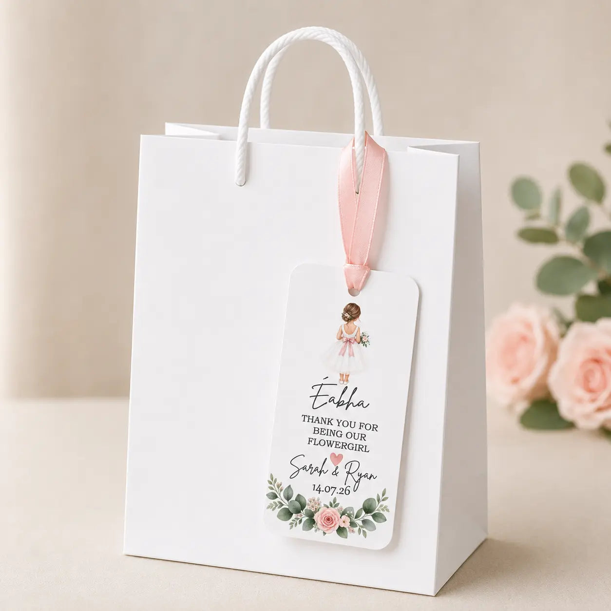 Personalised Flower Girl wedding gift tag with name, wedding date, pink ribbon and floral design displayed on a white gift bag