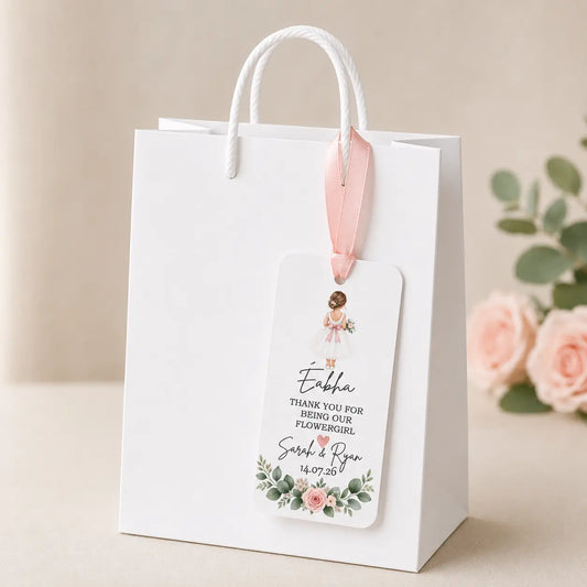 Personalised Flower Girl wedding gift tag with name, wedding date, pink ribbon and floral design displayed on a white gift bag