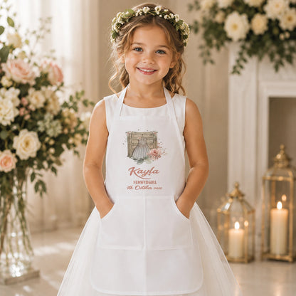 Young flower girl wearing a beautiful dress and a personalised white wedding apron with her name and wedding date, helping with wedding preparations while keeping her dress clean and protected.
