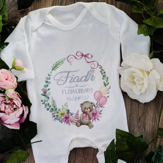 Personalised white Flowerbaby babygro featuring a teddy bear and floral wreath design, customised with baby’s name and date — printed and finished in Ireland by HanaLee Studios.