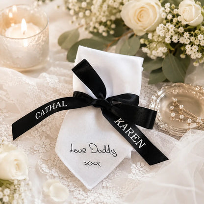 Personalised white memorial wedding handkerchief featuring a loved one's handwritten message, tied with a personalised black satin ribbon printed with the bride and groom's names.