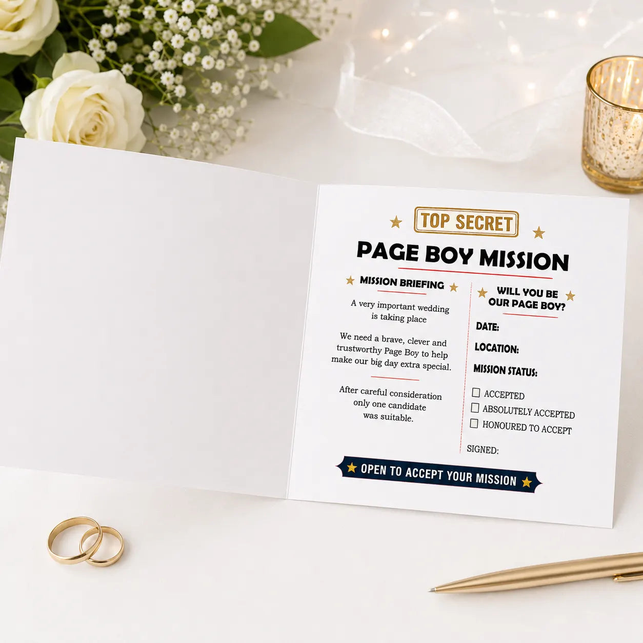 Open square white Page Boy Mission proposal card displayed on a white wedding-themed table with roses, candlelight and wedding rings. The inside right page features a mission briefing, page boy proposal message, wedding date and location fields, and mission acceptance checkboxes.