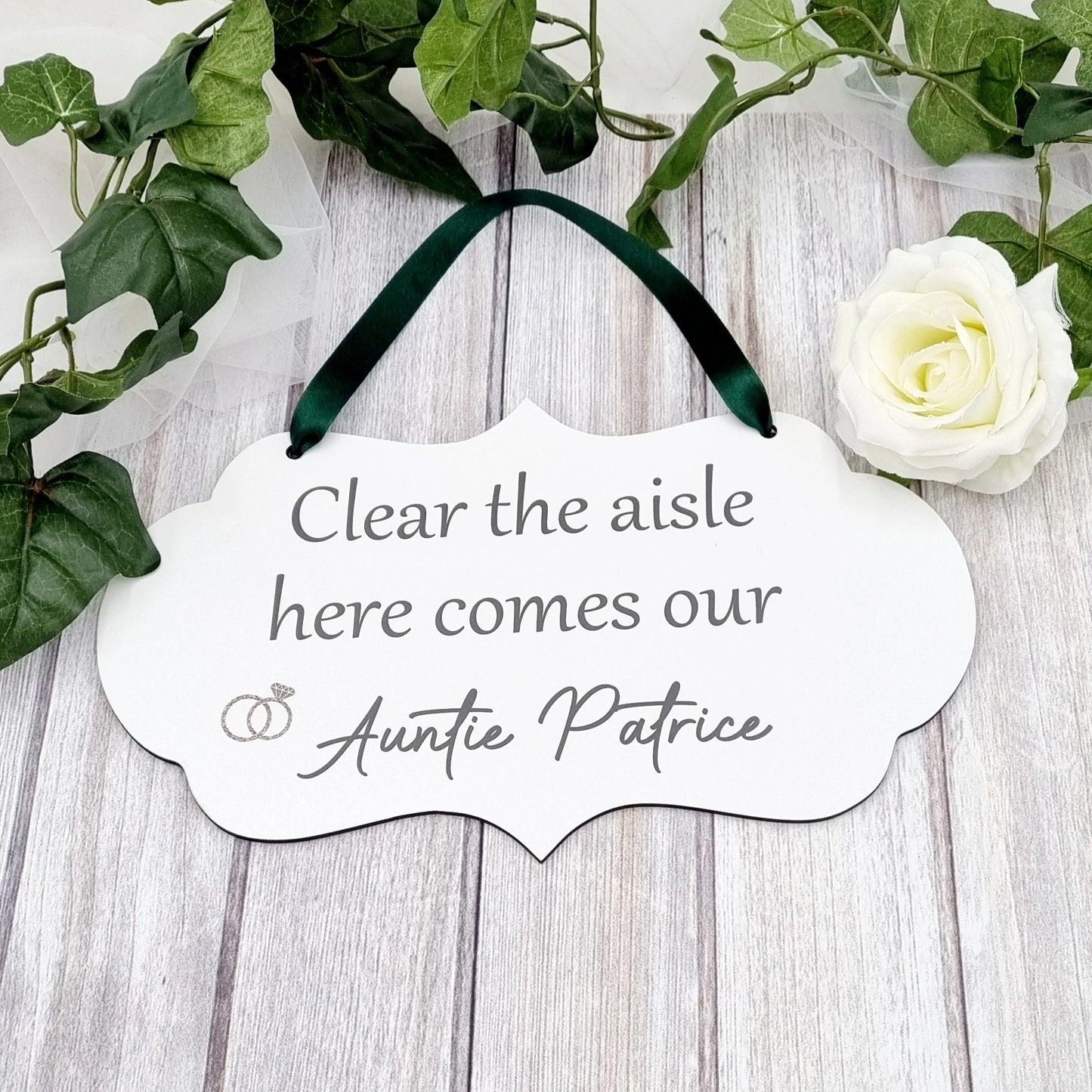 Flower girl or page boy wedding sign with green ribbon reading “Clear the aisle here comes our Auntie Patrice”