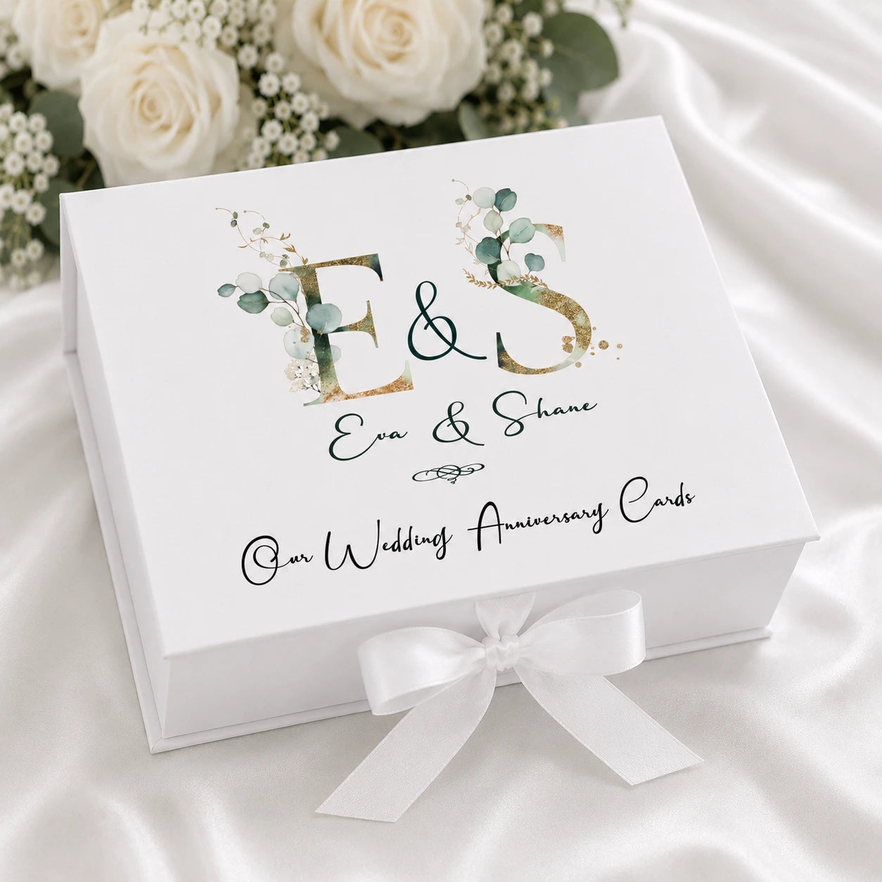 White personalised wedding anniversary card keepsake box with ribbon closure, featuring a botanical gold monogram design and couple's names.