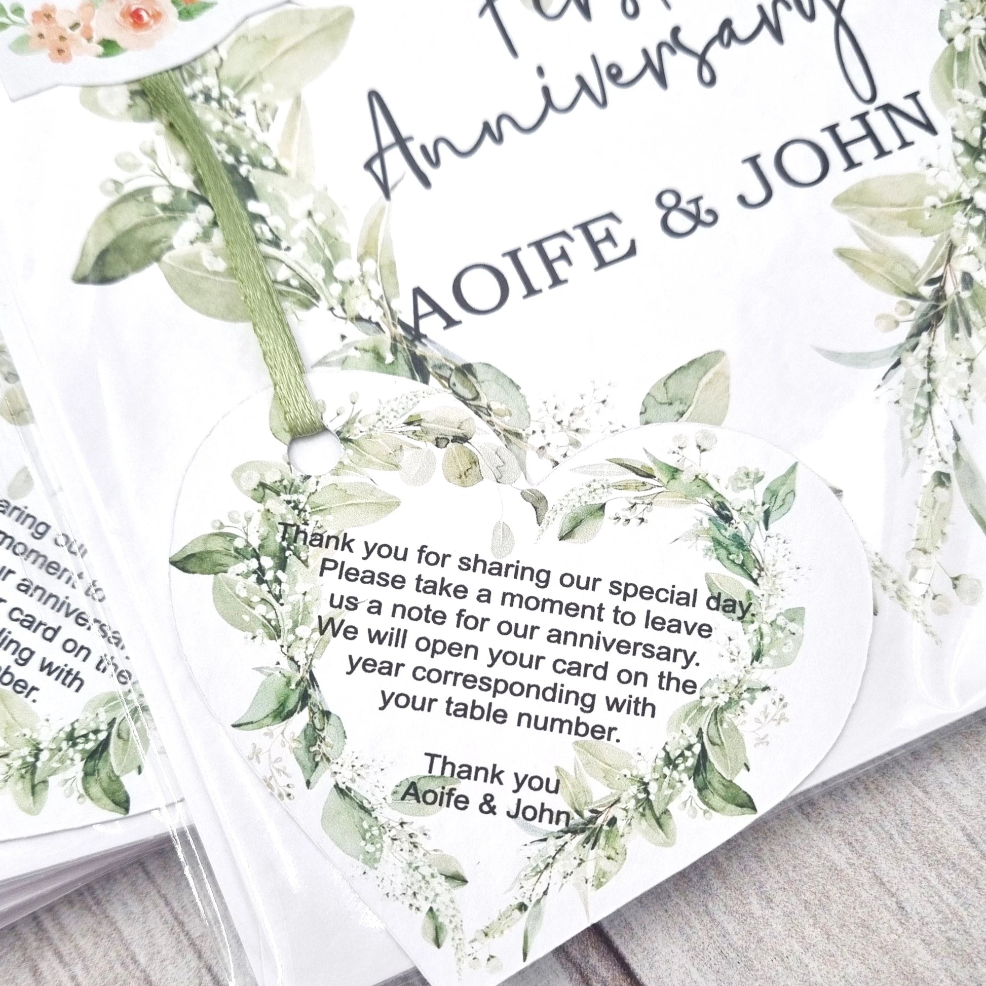 Close-up of personalised wedding anniversary table card heart message tag with eucalyptus greenery design, custom names Aoife and John – Irish wedding keepsake by HanaLee Studios