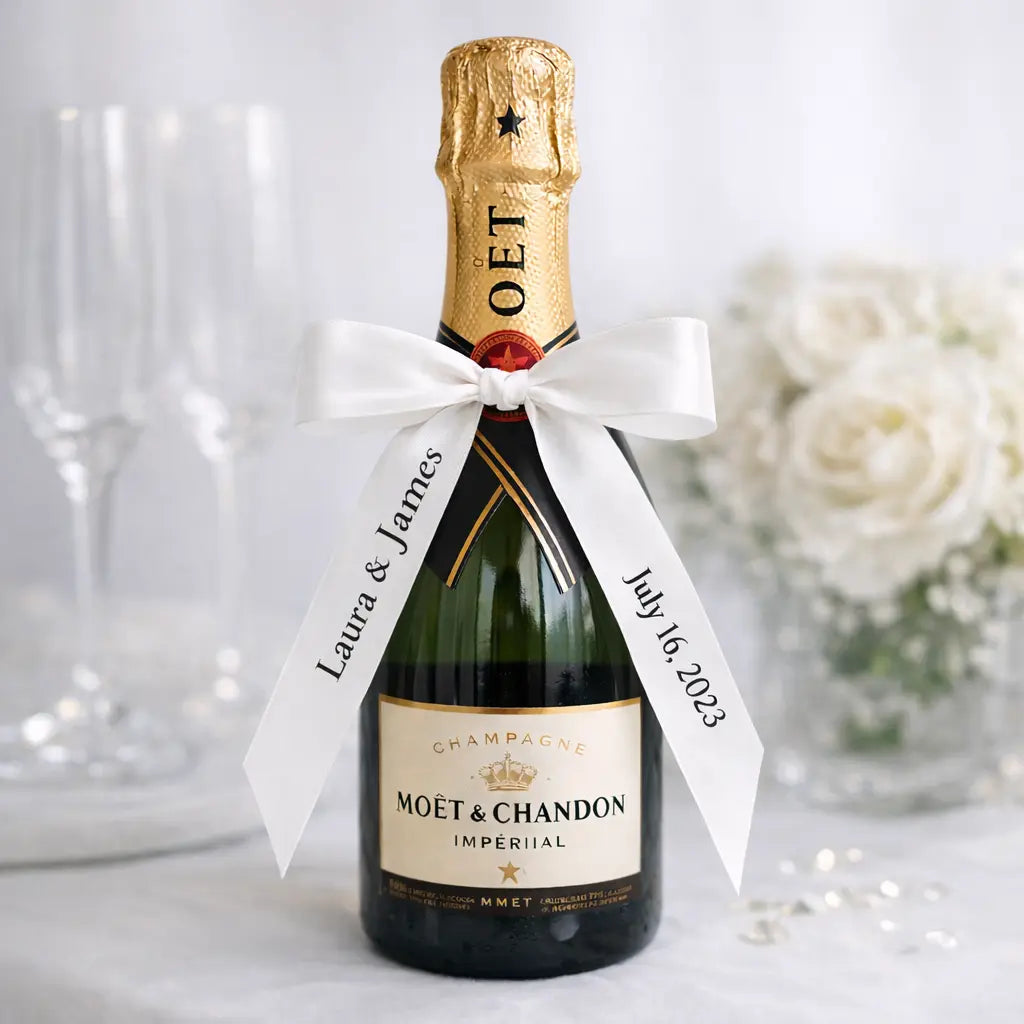 white satin personalised wedding ribbon with names and date tied around champagne bottle