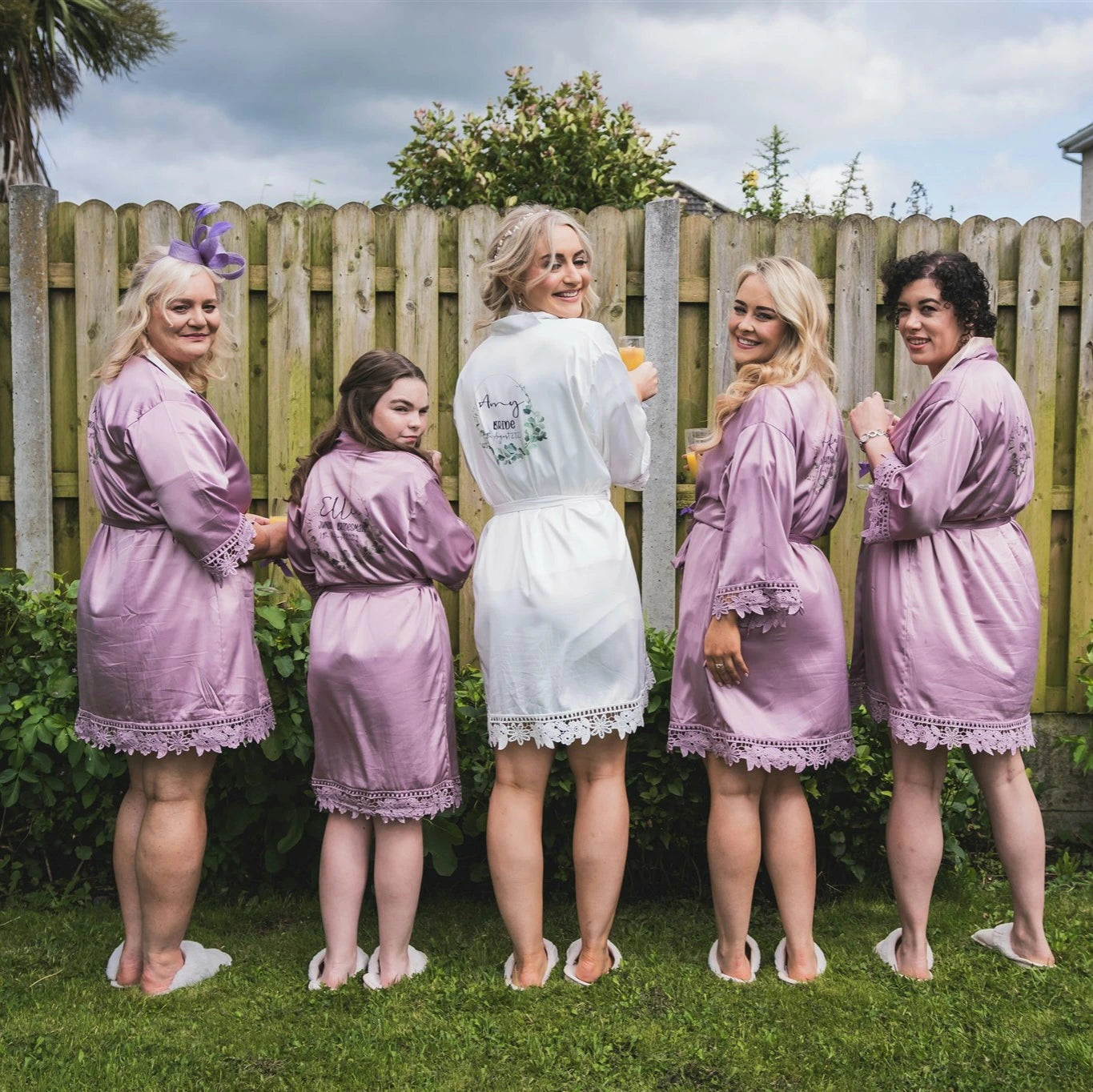 Bride and bridesmaids wearing personalised white and mauve wedding robes 