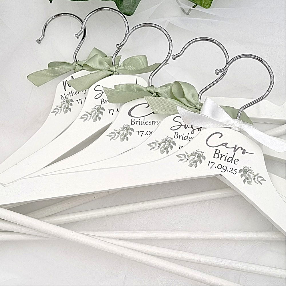 White wedding hangers personalised with bride bridesmaid details and a sage green bow