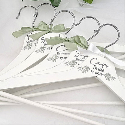 White wedding hangers personalised with bride bridesmaid details and a sage green bow