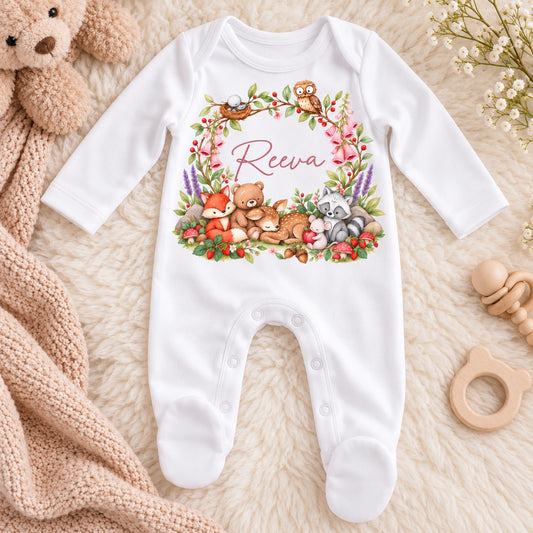 White personalised baby girl sleepsuit featuring woodland animal illustrations, pink flowers and baby's name printed on the front.